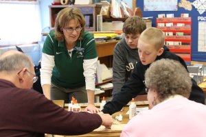 Mrs. Rehberger and her students assist visiting grandparents in building a plank road
